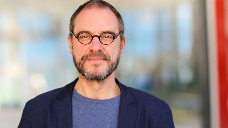 Prof. Kollmorgen mit Brille und Sakko lächelt in die Kamera.