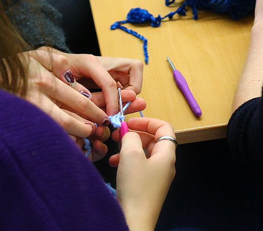 Two hands hold a crochet hook and crochet.