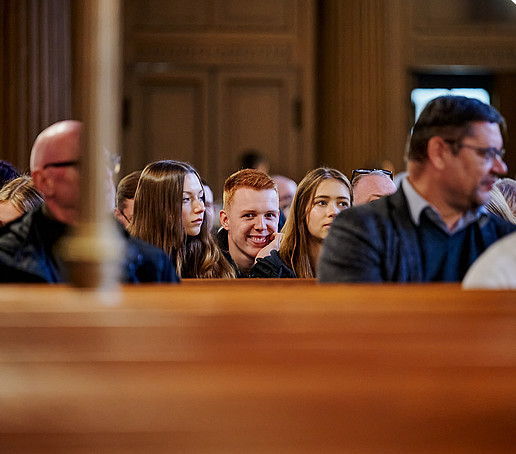 Sitzreihe in der Kirche mit Gästen.