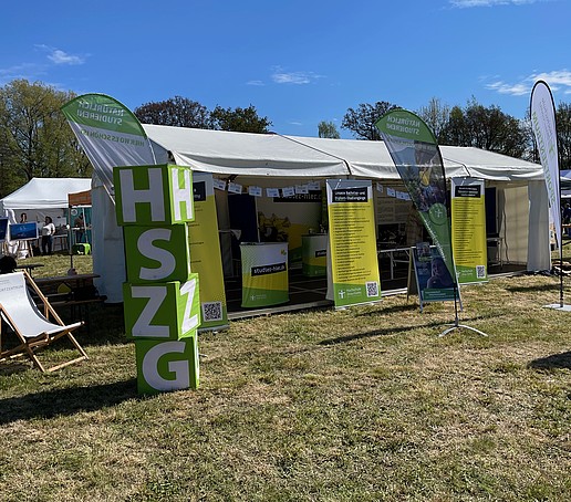 Der aufgebaute Zelt auf der Festwiese. Davor stehen HSZG-Würfel und Roll-ups.