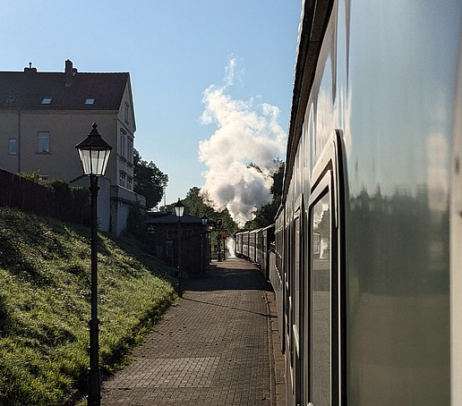 The moving steam locomotive under a blue sky.