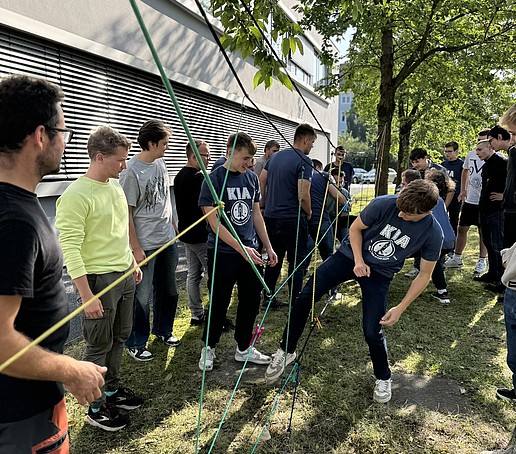 Studierende spielen auf einer Wiese mit Seilen.