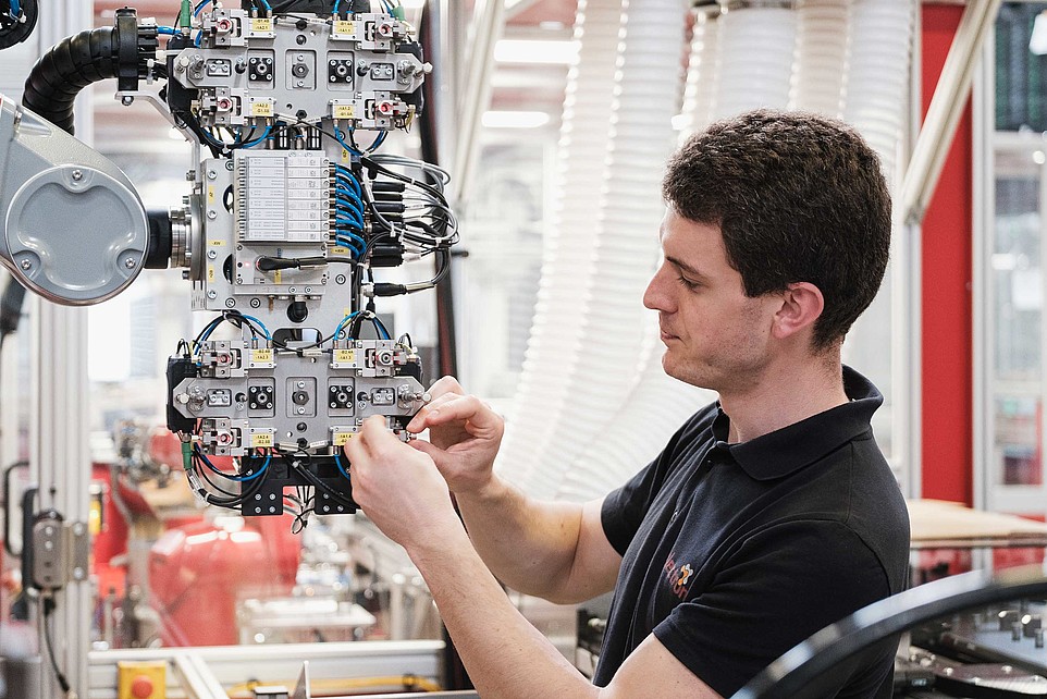 Man in a black polo shirt working on a complex machine.