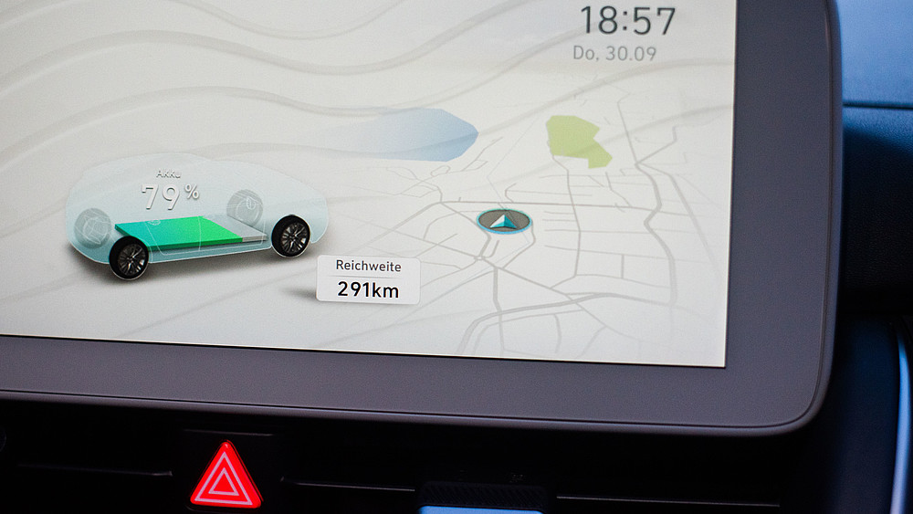 Auf einem digitalen Bildschirm ist eine digitale Landkarte mit einem digitalen Elektroauto zu sehen. Es wird die noch verfügbare Reichweite von 291 km angezeigt.