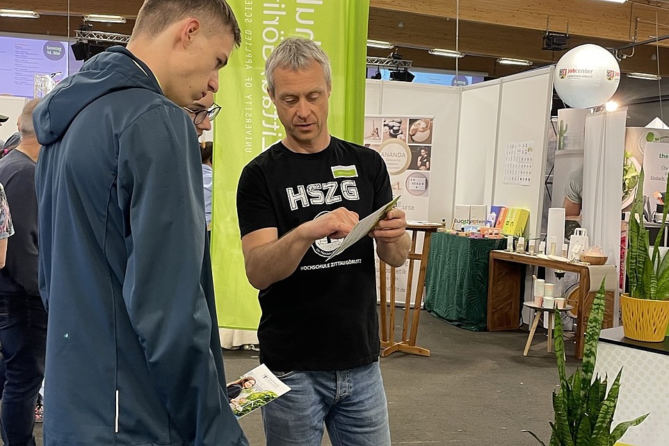 An HSZG employee advises a prospective student at the stand.