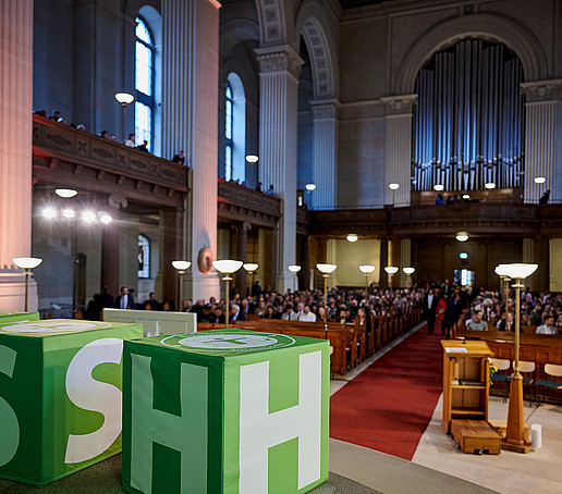 Blick vom Altar auf volle Sitzreihen der Kirche.