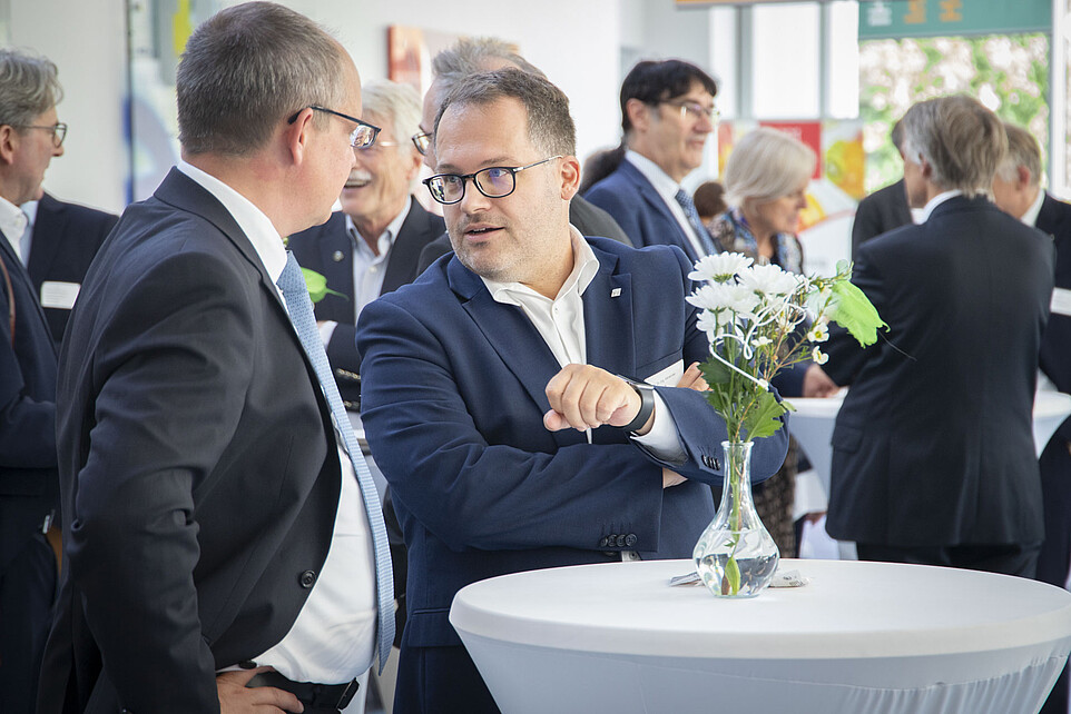 Rektor am Stehtisch im Foyer von Haus vier im Gespräch mit einem Gast