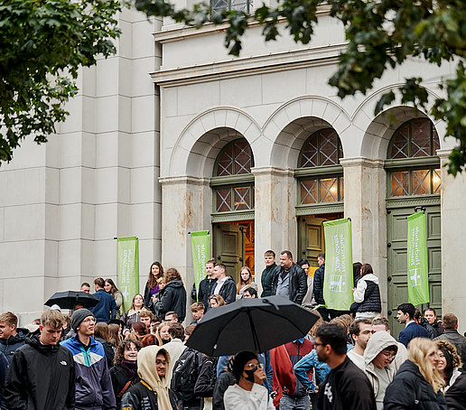 Die Gäste verlassen die Kirche über den Haupteingang und öffnen draußen ihre Schirme.