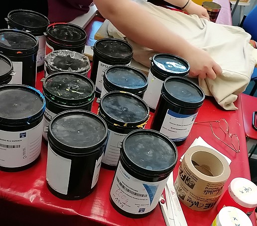 Various ink pots for screen printing on a table.