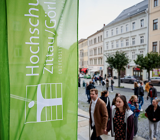 HSZG-Flagge vor der Johanniskirche, Gäste gehen Stufen hinauf.