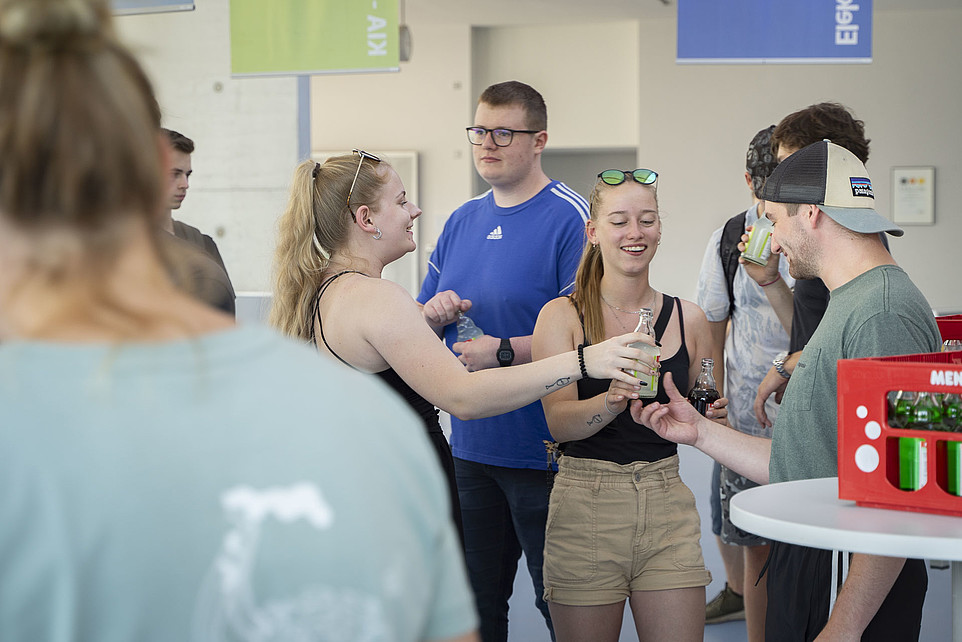 Dual students hand each other bottles that the Cobot has opened.