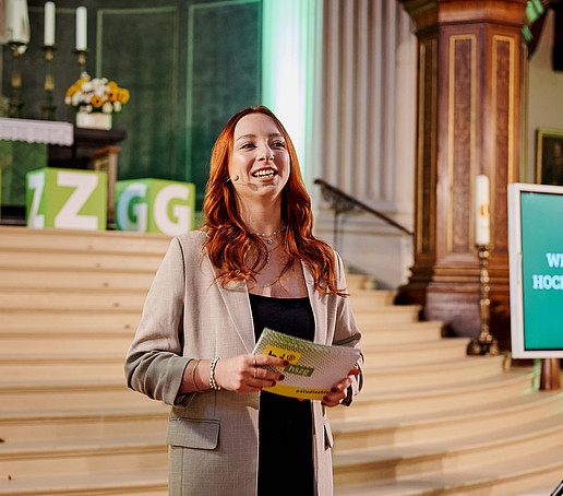 Moderatorin vor dem Altar mit Blick zum Publikum