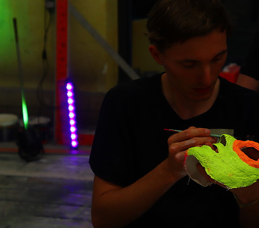 A mask painted with neon colors glows in the black light.