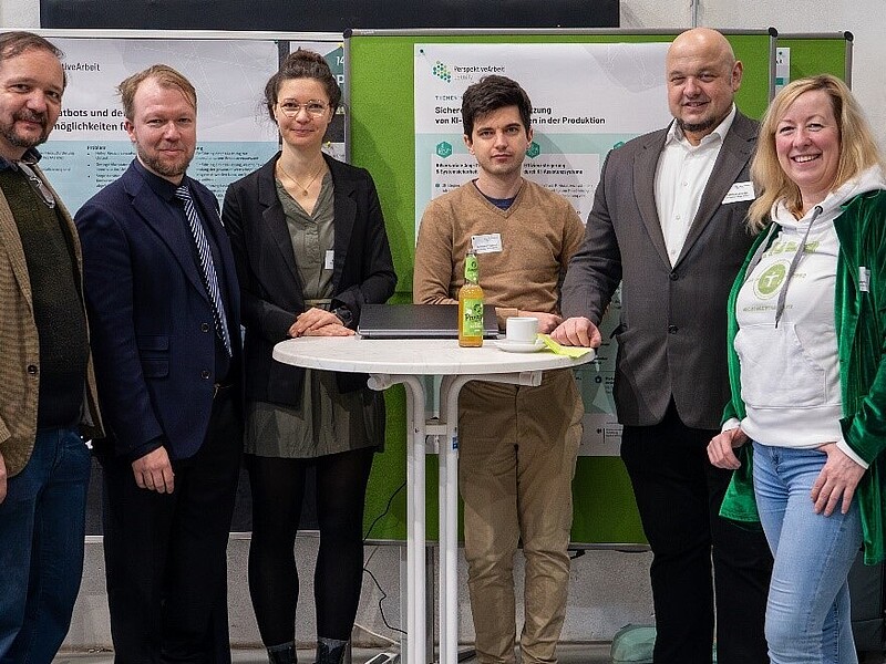 Das PAL-Team der Hochschule Zittau/Görlitz steht um einen weißen Stehtisch herum und lächelt in die Kamera.