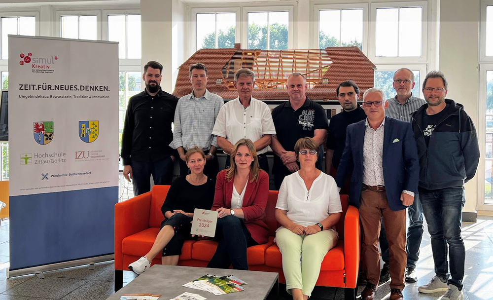 Group picture in front of the model of a half-timbered house