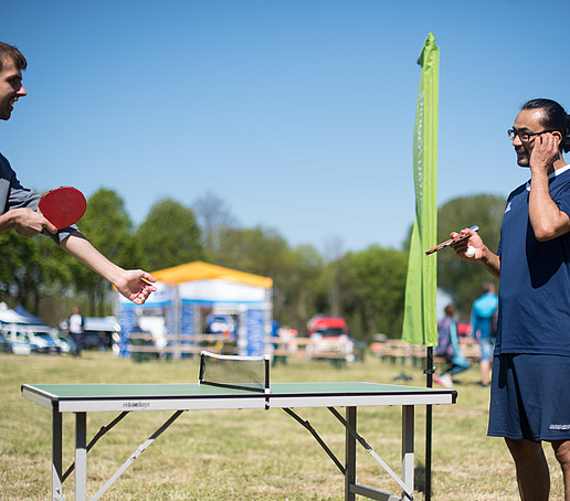 Zwei Spieler spielen Tischtennis vor dem Zelt.