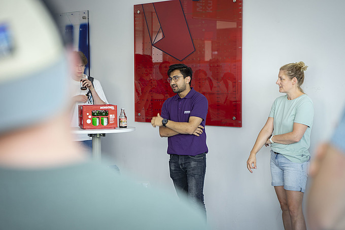 A KIA student explains something to the audience in the foyer of building four.