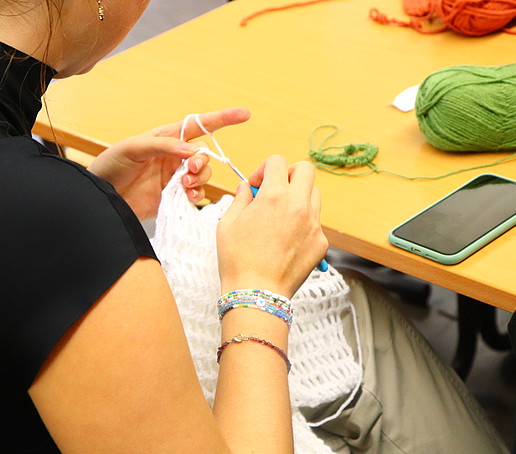 Two hands hold a crochet hook and crochet.