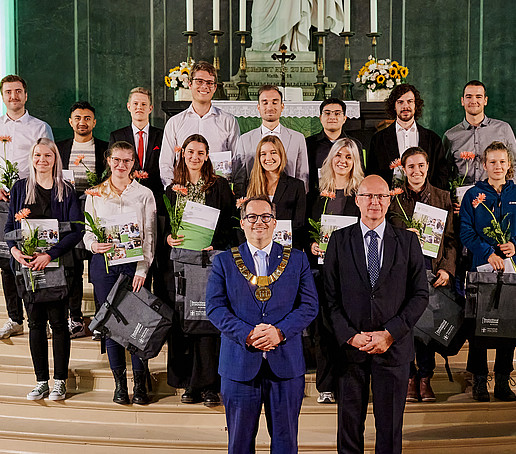 Gruppenbild mit Rektor, dem Hochschulratsvorsitzenden und den Deutschlandstipendiatinnen und -stipendiaten. Sie stehen auf den Stufen des Altars.