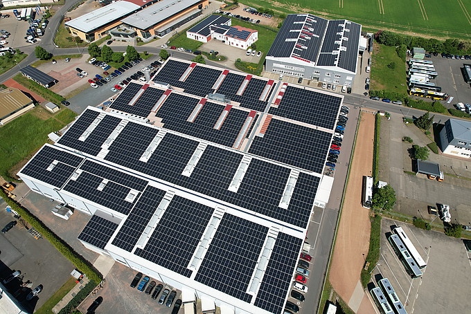 Aerial view of an industrial plant with large solar panels on the roofs.